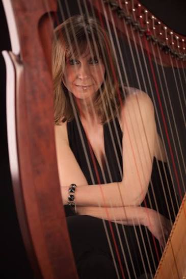 Portrait of Siân James seen through the strings of her harp